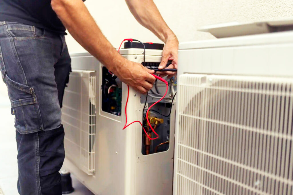 Technician from an air conditioning repair company testing an open AC unit with a multimeter